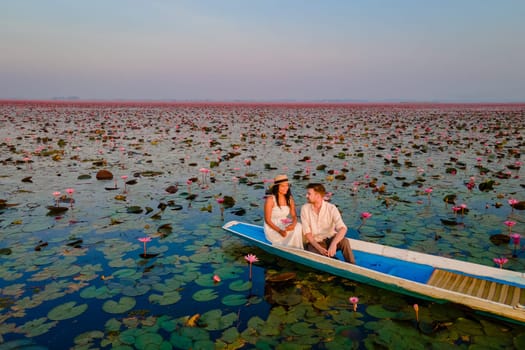 The sea of red lotus, Lake Nong Harn, Udon Thani, Thailand, a couple of men and woman in a boat at sunrise at the Red Lotus Lake in the Isaan at sunrise