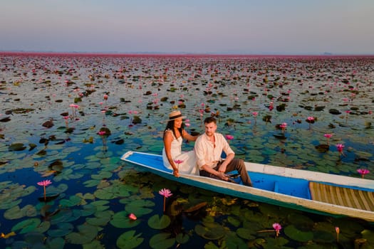 The sea of red lotus, Lake Nong Harn, Udon Thani, Thailand, a couple of men and woman in a boat at sunrise at the Red Lotus Lake in the Isaan at sunrise