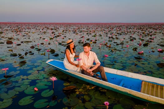 Sunrise at the sea of red lotus, Lake Nong Harn, Udon Thani, Thailand, a couple of men and woman in a boat at sunrise at the Red Lotus Lake in the Isaan