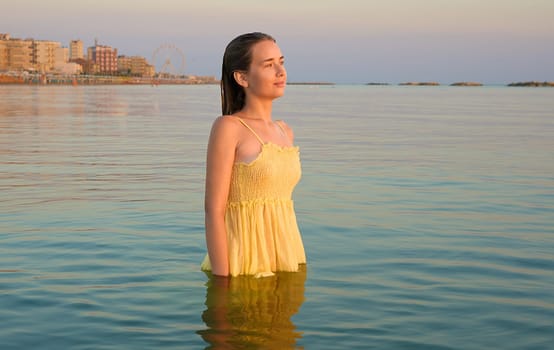 Young female traveler posing on the beach by the sea at sunrise and sharing her adventure travel.