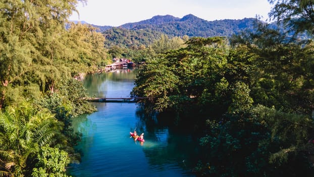 Couple men and women peddling in a kayak during the afternoon at sunset, People in a Kayak at a river klong of a tropical Island Koh Chang Thailand during sunset