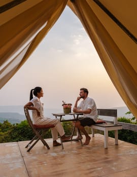 A couple of men and women watching the sunset at a mountain camping in Phitsanulok Thailand. luxury glamping in the mountains nature