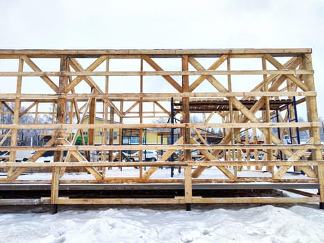 Wood frame house under construction, bare frame and walls with pile foundation, winter season