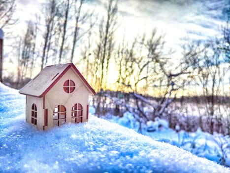 Wooden toy house on snow, natural abstract background. winter season concept. symbol of cozy, loving family home. construction, sales, rental concept. Christmas and new year holidays. copy space
