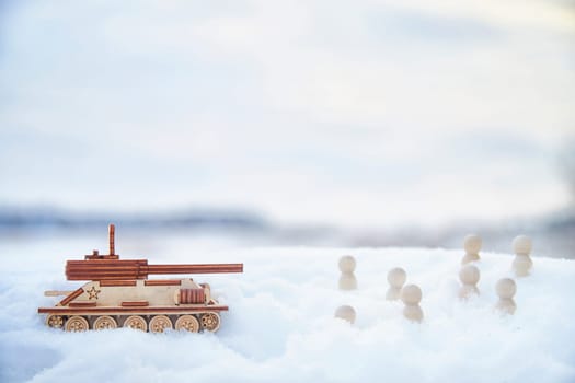 Wooden toy Russian tank T-34 and little men in the snow. Russia and Ukraine are at war in winter. Encirclement, retreat, attack, victory