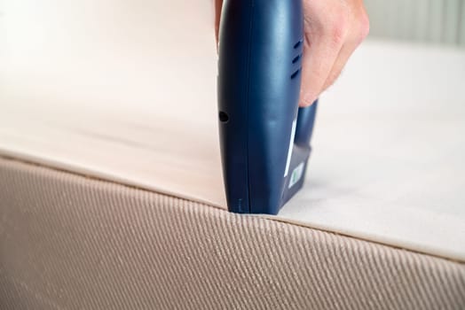 Worker stapling sofa lining with electric staple gun