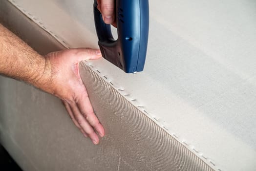 Worker stapling sofa lining with electric staple gun