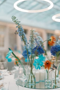 Orange and blue flowers in glasses on the table in a restaurant. High quality photo