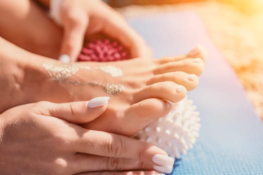 Middle aged well looking woman with black hair doing Pilates with the ring on the yoga mat near the sea on the pebble beach. Female fitness yoga concept. Healthy lifestyle, harmony and meditation.