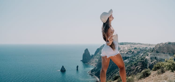 Woman travel sea. Young Happy woman in a long red dress posing on a beach near the sea on background of volcanic rocks, like in Iceland, sharing travel adventure journey