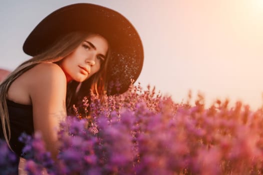 Close up portrait of young beautiful woman in a white dress and a hat is walking in the lavender field and smelling lavender bouquet.