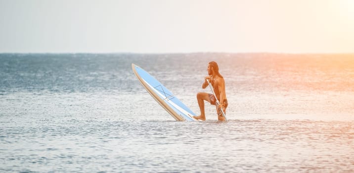 Asian man swimming in sea water and paddleboarding passing beautiful sea at summer sunset. Healthy strong male enjoy outdoor active lifestyle and water sports on holiday vacation