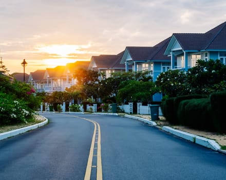 Modern cottages row road sidewalk two story buildings residential villas village New Estate Reflection dawn Sun in windows.