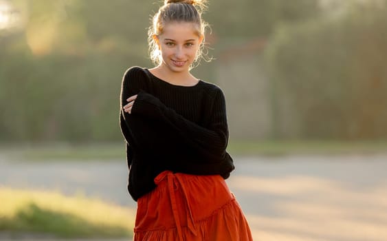 Beautiful teenager girl posing in park outdoors at nature. Pretty teen model in trendy clothes at street portrait