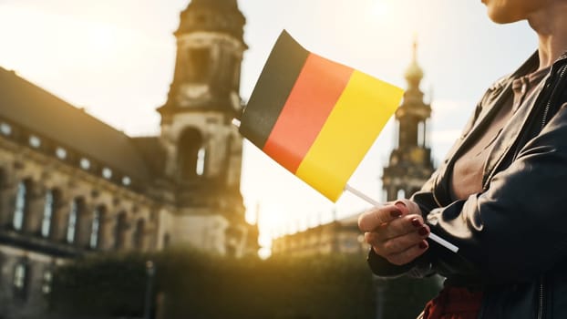 Young Woman Holds German Flag In Hand, With Blurred City Background In Autumn