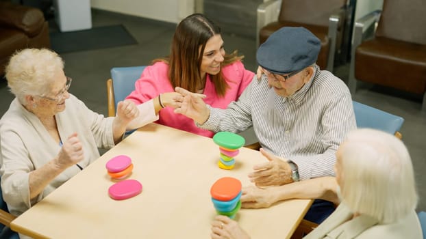 Photo of a senior man resolving a complicated skill game in a geriatrics and people congratulate him