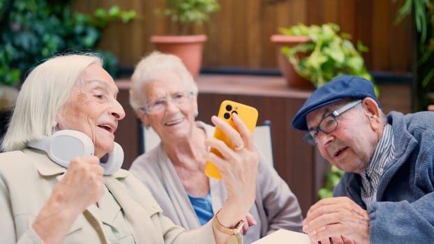 Picture of three senior people of a geriatric using phone and smiling