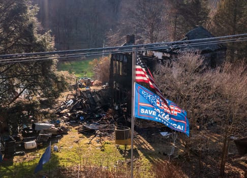Morgantown, WV - 24 December 2023: Burned out home behind a US and Trump 2024 flag as concept for election campaign collapse
