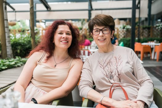 Happy mature mother and her adult daughter enjoying in conversation while spending Mother's day together in a cafe.