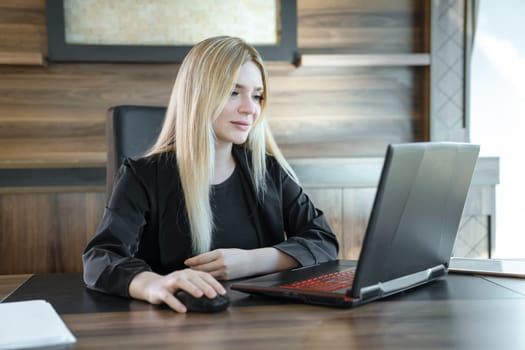 Young female teacher is sitting in front of laptop conducting lesson, concept of online teaching.