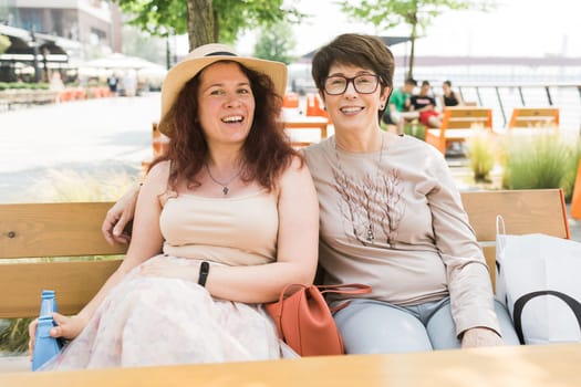 Happy mature mother and her adult daughter enjoying in conversation while spending Mother's day together in a cafe.