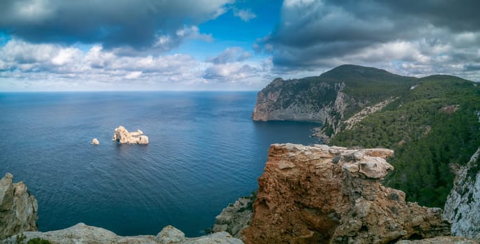 Coastal scene with high cliffs and tranquil sea under cloudy skies.