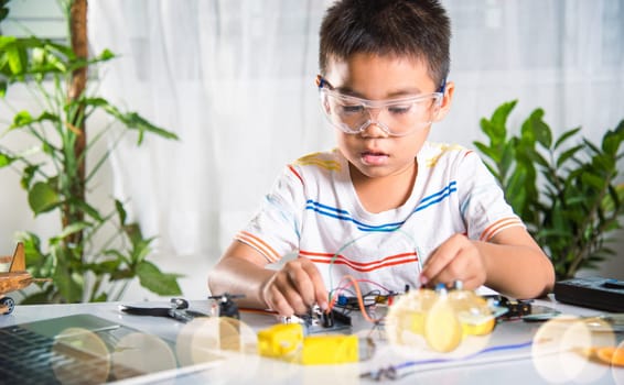 Asian kid boy plugging energy and signal cable to sensor chip with Arduino robot car, Little child remotely learn online with car toy, STEAM education AI technology course school learning lesson