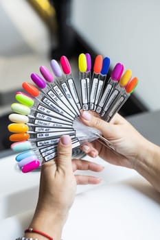 Collection of nails color polish samples. A palette of nail designs of different colors with gel polish. Transparent tips with nail polish samples. Demonstration fan-shaped palette of color shades