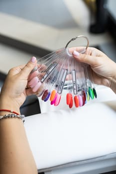 Collection of nails color polish samples. A palette of nail designs of different colors with gel polish. Transparent tips with nail polish samples. Demonstration fan-shaped palette of color shades