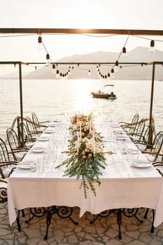 Festive table with bouquets of flowers stands on a terrace by the sea. High quality photo
