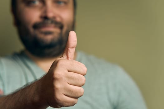 A bearded European man shows hand sign super
