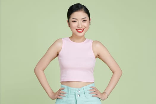 Happy asia female posing with arms on hips and looking at camera