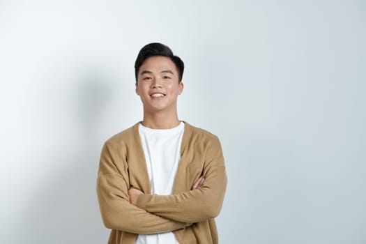 young handsome man standing with crossed arms, isolated on studio white background