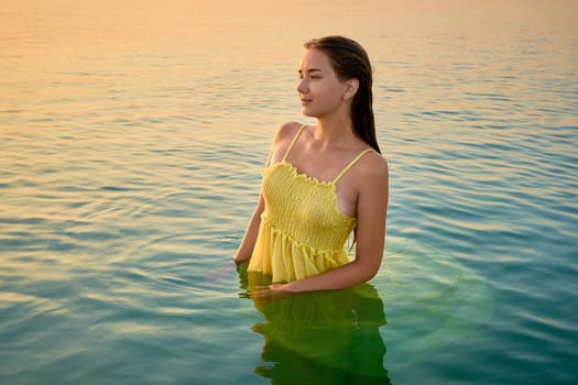 beautiful girl in a wet yellow dress in the water