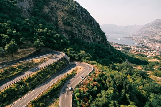 Cars drive along a serpentine road in the green mountains above the Bay of Kotor. Montenegro. High quality photo