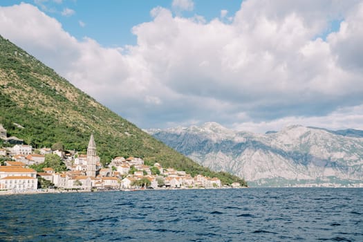 View from the sea of the ancient town of Perast with a high bell tower among stone houses. Montenegro. High quality photo