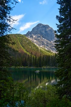 Incredibly beautiful transparent emerald calm lake with reflection of rocky mountain on the Black Prince Cirque Trail. Majestic Canadian mountains with snow on sunny summer day in Alberta, Kananaskis.