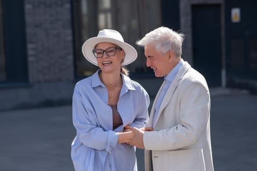 Stylish elderly laughing couple on a walk. Romantic relationships of mature people