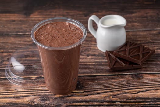 Chocolate milk in take away glass on wooden table