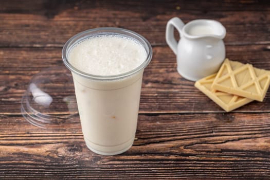 White Chocolate milk in take away glass on wooden table