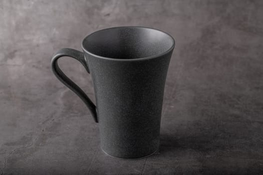 Empty black porcelain cup on gray stone background