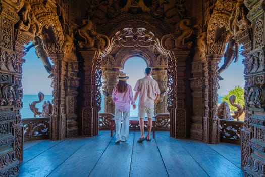 A diverse multiethnic couple of men and women visit The Sanctuary of Truth wooden temple in Pattaya Thailand, wooden temple of Pattaya