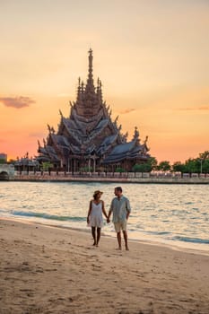 A diverse multiethnic couple of men and women visit The Sanctuary of Truth wooden temple in Pattaya Thailand. a wooden temple construction located at the cape of Naklua Pattaya City Chonburi