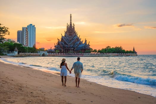 A diverse multiethnic couple of men and women visit The Sanctuary of Truth wooden temple in Pattaya Thailand. a wooden temple construction located at the cape of Naklua Pattaya City Chonburi