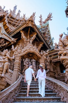 A diverse couple of men and women visit The Sanctuary of Truth wooden temple in Pattaya Thailand. a wooden temple construction located at the cape of Naklua Pattaya City Chonburi Thailand