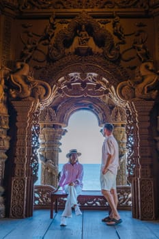 A couple of men and women visit The Sanctuary of Truth wooden temple in Pattaya Thailand. a wooden temple construction located at the cape of Naklua Pattaya City Chonburi Thailand