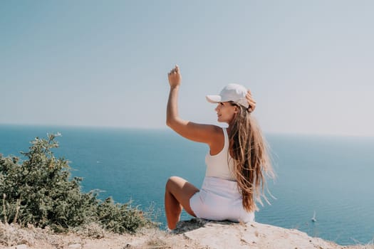 Woman travel sea. Young Happy woman in a long red dress posing on a beach near the sea on background of volcanic rocks, like in Iceland, sharing travel adventure journey