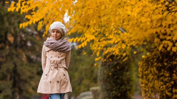 Caucasian girl in a beige coat and beret walks in the park in autumn