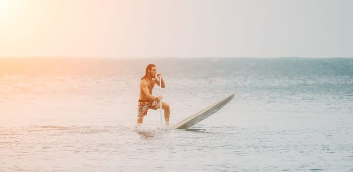 Asian man swimming in sea water and paddleboarding passing beautiful sea at summer sunset. Healthy strong male enjoy outdoor active lifestyle and water sports on holiday vacation