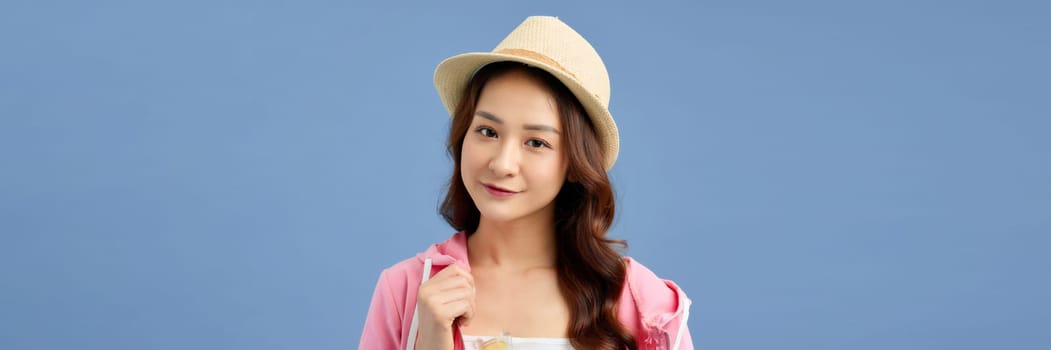 young attractive Asian woman traveler in casual clothes wearing straw hat over blue
